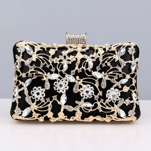 Macro detail of black dinner clutch with golden floral hollow patterns and inlaid rhinestones