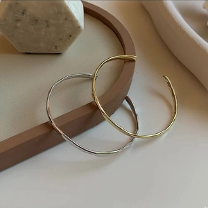 Close-up of gold and silver irregular hammered texture cuff bracelets in minimalist style