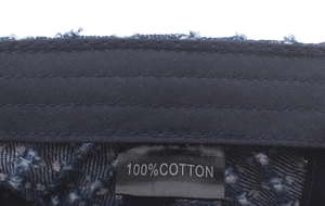 Close-up of 100% cotton inner tag and denim texture on the blue newsboy cap