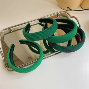 Set of four vintage green sponge headbands with assorted textures on a silver tray