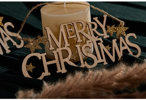Detail of wooden Merry Christmas hanging sign with golden glitter stars and jute rope