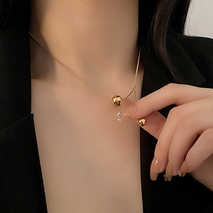 Elegant gold titanium ball pendant on snake chain necklace for women worn with black suit