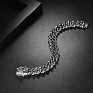 Detailed close-up of a silver skull clasp on a chunky stainless steel Cuban chain bracelet