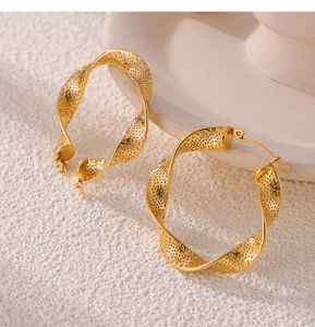 Macro view of gold plated twisted hoop earrings with geometric cutout patterns