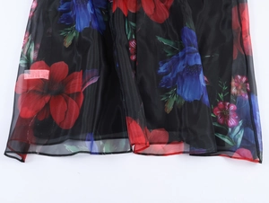 Gros plan détaillé d'une robe longue en organza avec imprimé floral rouge et bleu sur noir