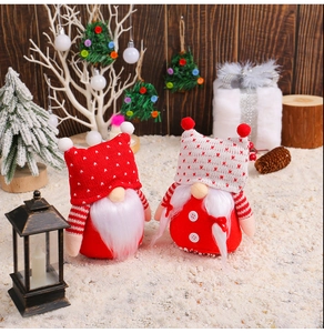 Close-up of two Christmas plush gnomes with knitted hats on a snowy festive background
