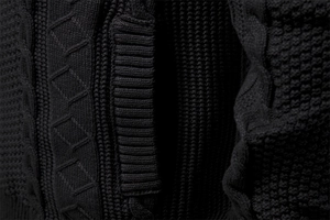 Dettaglio macro di giacca in maglia nera con trecce e trama a nido d'ape definita