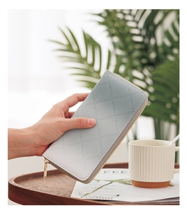 Close-up of light blue quilted PU leather wallet held by a model in a cozy lifestyle setting