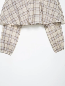 Close-up of lightweight plaid long sleeve top with elastic cuffs and ruffle hem detail