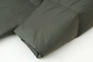 Macro detail of dark green padded jacket showing windproof fabric and precise stitching
