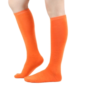 Detail of knee-high orange cotton knit socks with sporty three-stripe design on leg