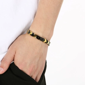 Close-up of men's tungsten steel bracelet with gold and black magnetic links on wrist