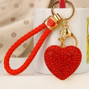 Close-up of red rhinestone heart keychain with a matching woven leather strap and gold ring