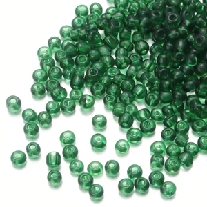 Macro shot of 2-3mm green transparent rainbow glass seed beads on a white background