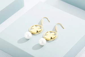 Detailed shot of golden angel hoop earrings with white pearls on a blue display stand