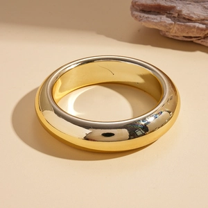 Detail of minimalist wide golden bangle with a high-polished mirror finish and stone accent