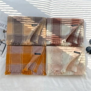 Flat lay of soft cashmere-feel scarves with fringe edges in diverse plaid patterns