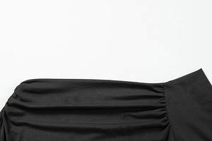 Detail of elegant black off-shoulder top showing pleated ruching texture and fabric finish