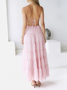 Back view of a pink halter neck dress featuring a backless design with tie-up details