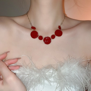 Gros plan d'un collier doré avec cinq pendentifs circulaires rouges sur un mannequin