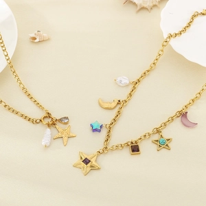 Détail du collier étoile et lune doré avec perles et gemmes sur texture de sable