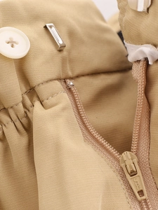 Détail de la taille d'une veste kaki avec bouton, fermeture éclair et crochet