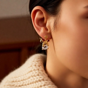 Close-up of 18k gold-plated unicorn earrings with red enamel and zircon on ear