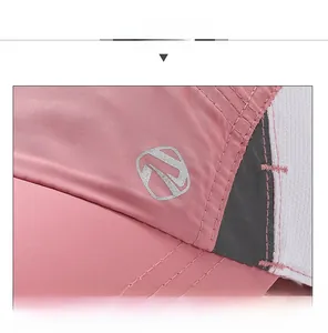 Detail of pink quick-dry cap showing breathable mesh, reflective strip and logo stitching