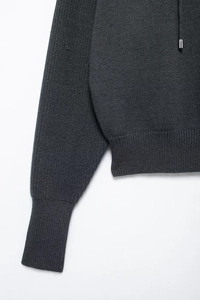 Detail view of dark grey knitted sweater featuring ribbed cuffs and fine textile texture