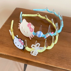 Close-up of cute wave headbands with resin kitten charms and bow details on wood