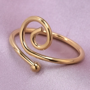 Macro view of gold minimalist spiral ring with sphere detail on purple silk fabric