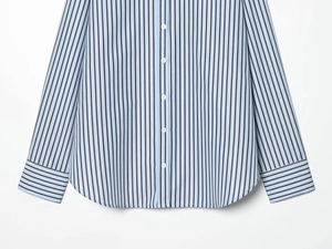 Detailed close-up of blue and black vertical striped poplin shirt hem with white buttons