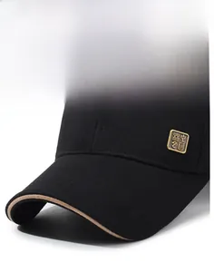 Detail of black canvas baseball cap showing metal logo plate and contrast brim piping