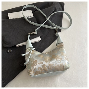 Detail of mint green silk jacquard bag with golden landscape embroidery and pearl pendant