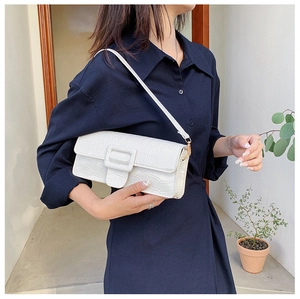 Detail of white crocodile pattern baguette bag with gold buckle on a navy blue dress