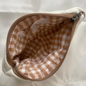 Top view of cream canvas cosmetic bag showing brown checkered lining and interior space