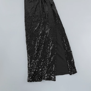Détail d'une robe noire à paillettes scintillantes avec fente latérale et doublure