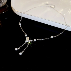 Macro detail of Y2K butterfly necklace with crystal inlay, faux pearls, and silver tassels