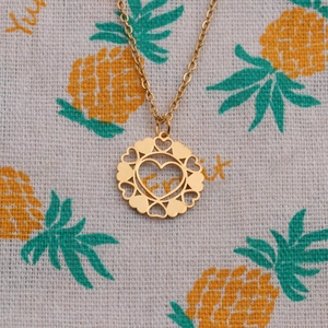 Polished gold stainless steel necklace featuring an open heart pendant on fruit print fabric