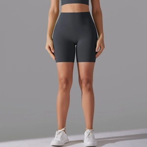 Detail view of high-waisted dark grey seamless sports shorts on a model with white shoes