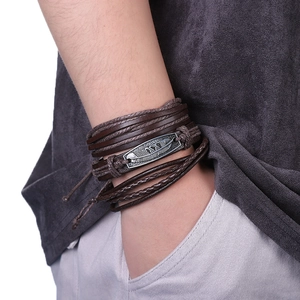 Détail d'un ensemble de bracelets multicouches en cuir pour homme avec plume rétro au poignet