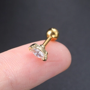 Macro shot of tiny gold zircon cartilage stud held by fingertips for size reference