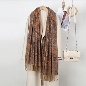 Detail of brown paisley scarf with tassels paired with beige coat and chain bag