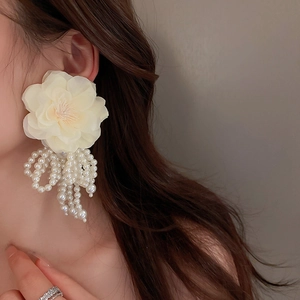 Detailed view of floral pearl tassel earring worn by a model with elegant cream fabric petals