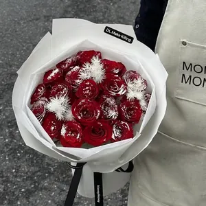 Red rose bouquet with snow effect decoration and festive white feather ornaments