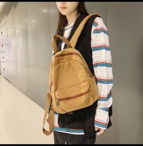 Khakibrauner Canvas-Rucksack mit Seitentasche, präsentiert am Rücken einer Person