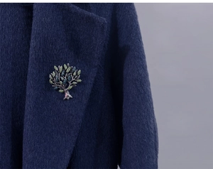 Close-up of tree of life brooch with green rhinestones pinned on a blue wool coat