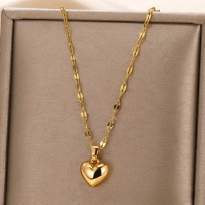 Detail of 18k gold heart pendant with flat leaf chain on silk textured jewelry box