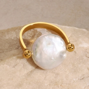 Bague en acier doré avec une perle baroque blanche posée sur une pierre naturelle