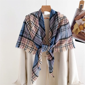 Detail of soft plaid scarf with tassels in blue, pink and beige on off-white coat